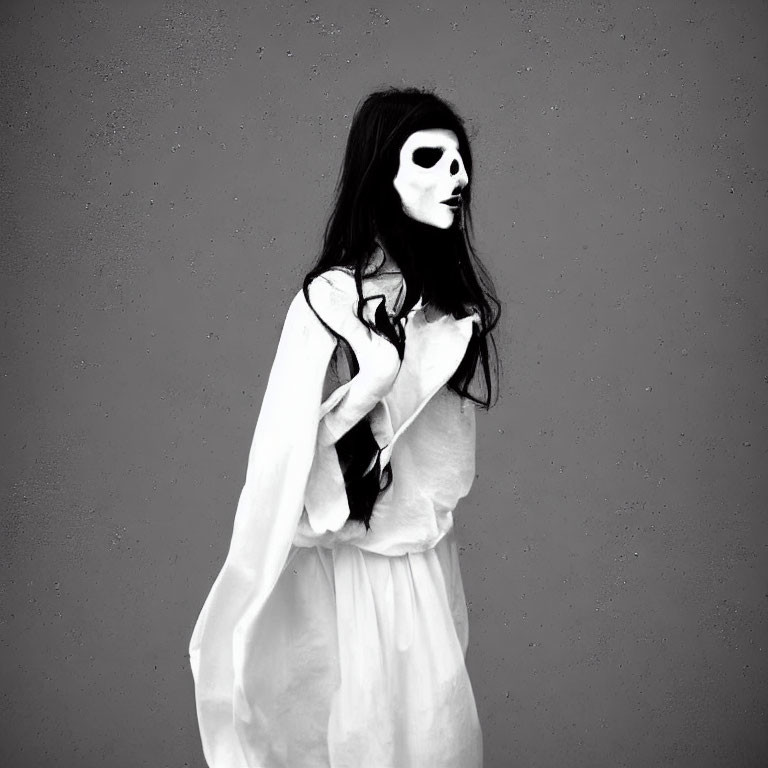 Person in white garment with skull-like face paint against gray background