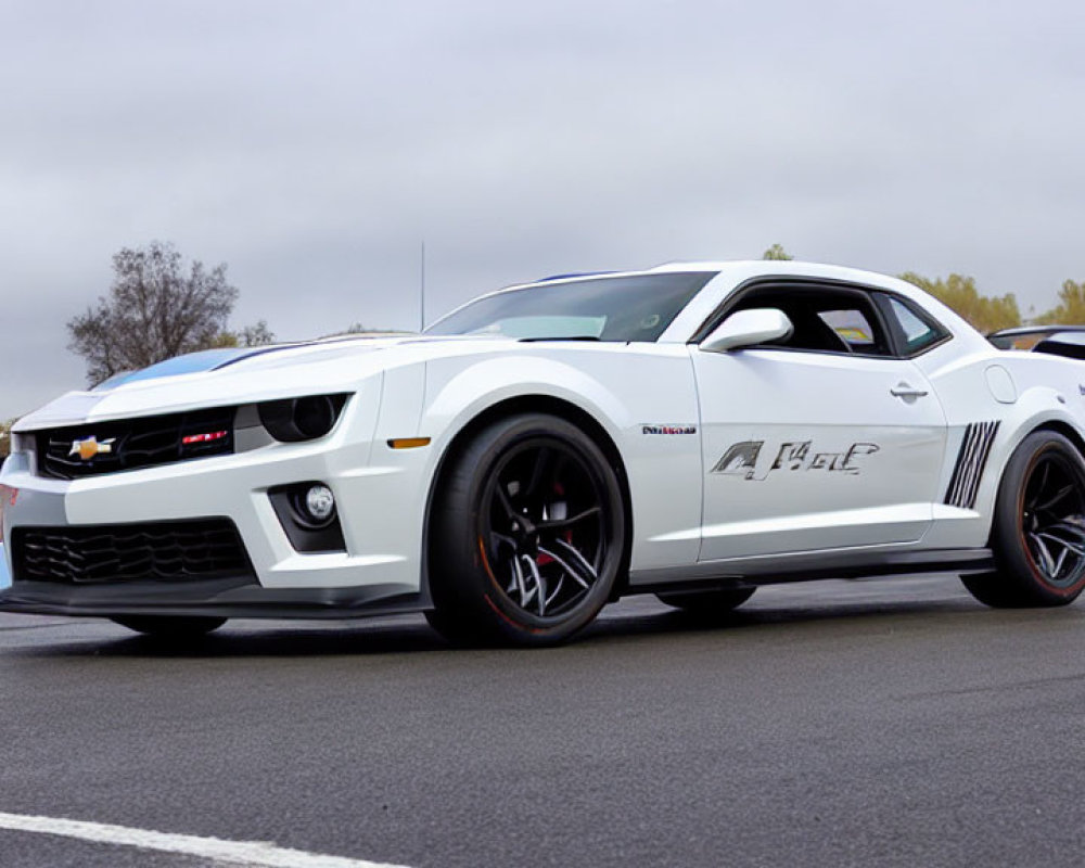 Customized white Chevrolet Camaro with black stripes showcased at outdoor event