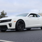 Customized white Chevrolet Camaro with black stripes showcased at outdoor event