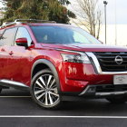 Red Nissan SUV with Chrome Detailing and Aftermarket Wheels on Asphalt Road