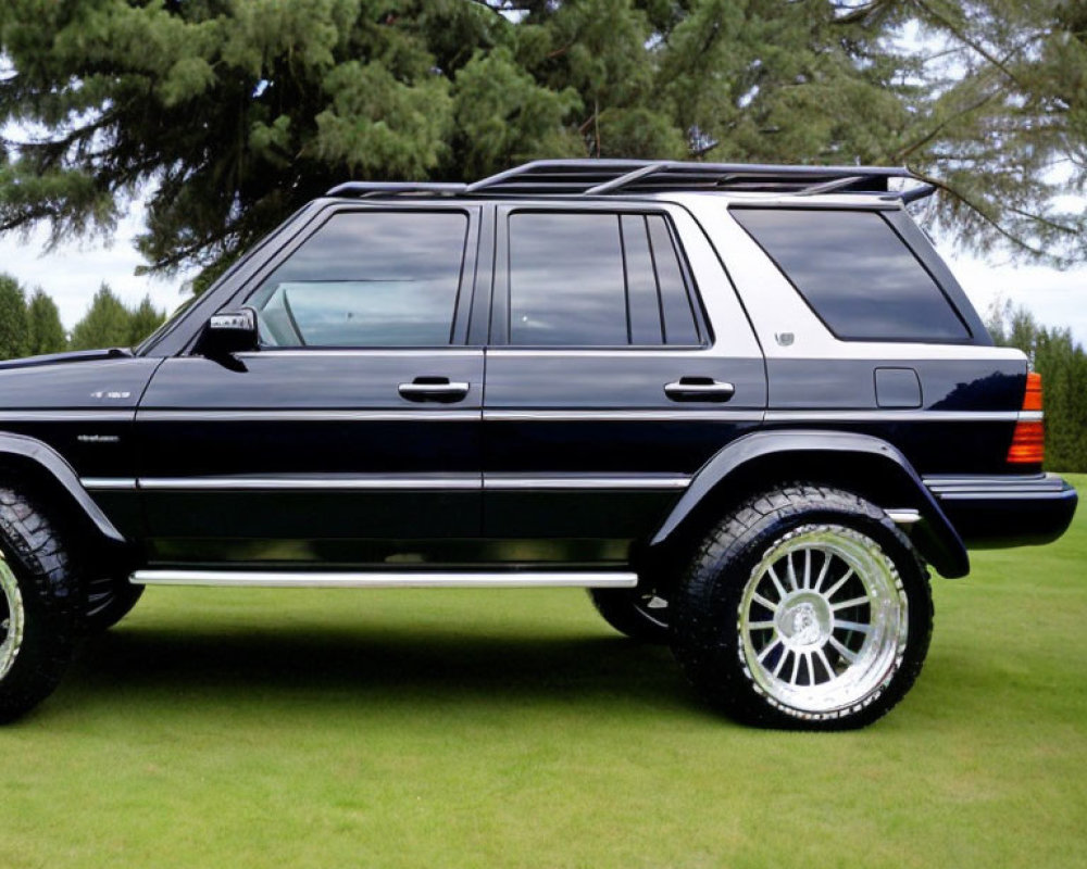 Black luxury SUV with chrome rims parked on green grass