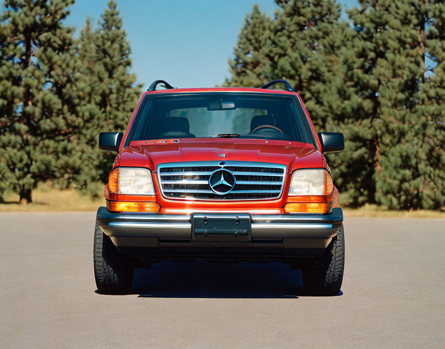 Red Mercedes-Benz Car Parked Outdoors with Blue Sky and Trees