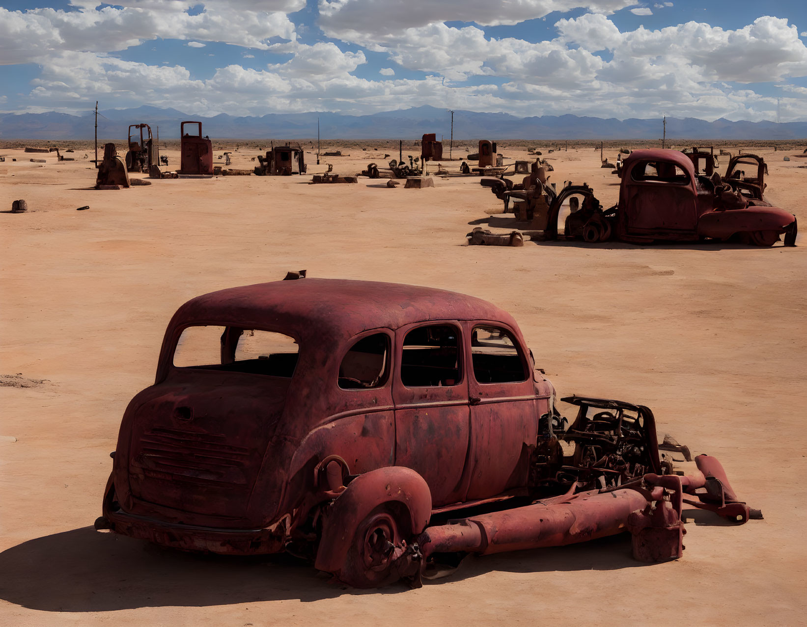 Abandoned rusty car in desert with scattered equipment