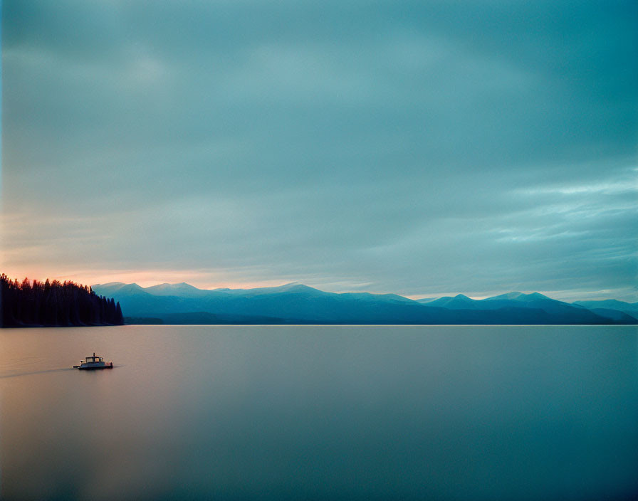 Tranquil lake scene with boat under golden-blue sky