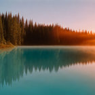 Tranquil lake reflects autumn forest in soft sunrise fog