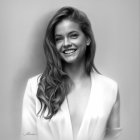 Monochrome portrait of woman with long wavy hair in V-neck blazer.