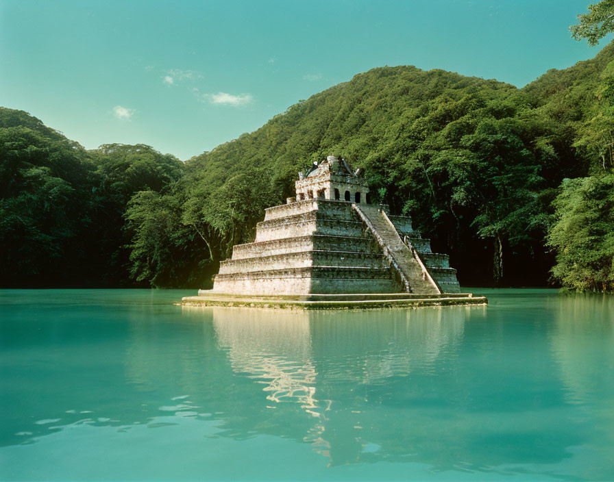 Ancient pyramid in water with lush forest and clear sky