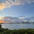 Sailing ships on tranquil waters at sunset with colorful skies and lush greenery