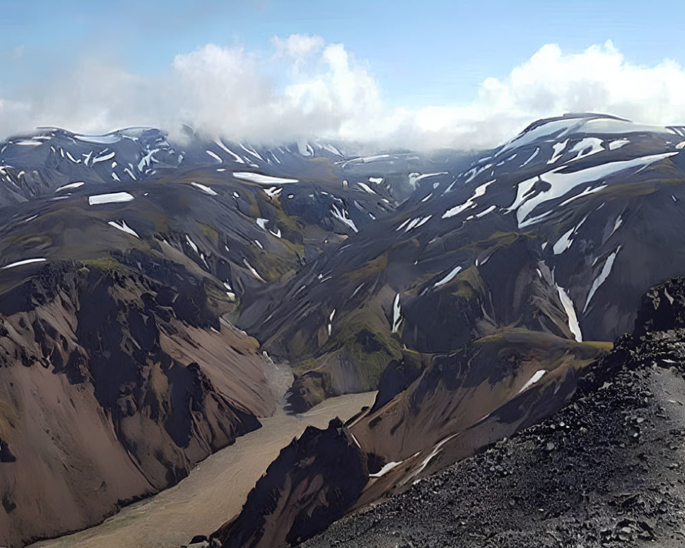 Panoramic rugged mountain landscape with snow patches under cloudy sky