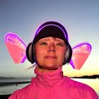 Woman in Pink Jacket with Glowing Cat Ear Headphones at Twilight