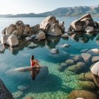 Tranquil landscape with blue waters, towering rocks, greenery, and pink blossoms