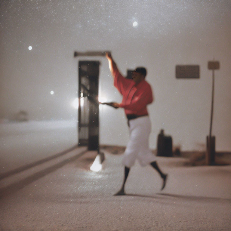 Person in red top swinging baseball bat at night with starry sky and road sign.