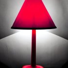 Red Conical Shade Lamp Illuminating Textured White Wall