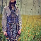 Plaid-coated child in field with yellow flowers and forest backdrop