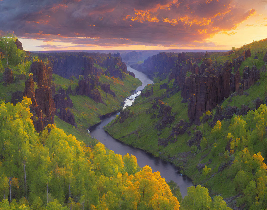 River winding through lush canyon under dramatic sunset sky