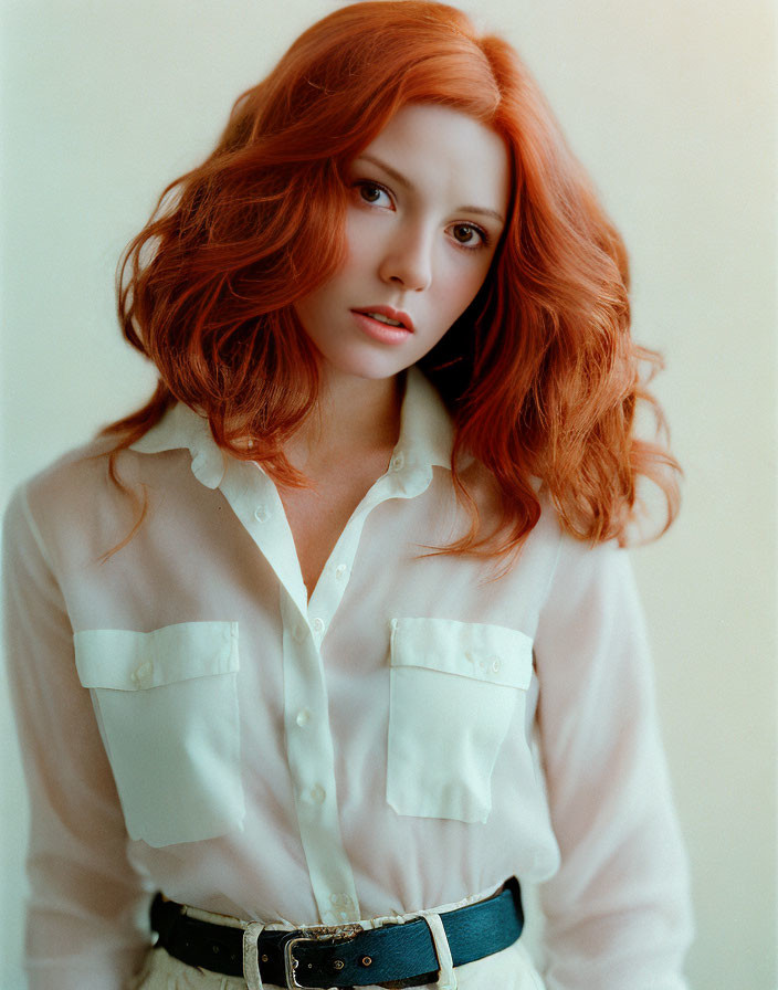 Vibrant red-haired woman in white shirt on beige background