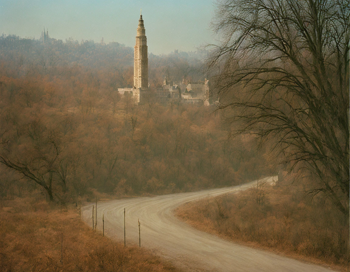 Misty autumn landscape with winding dirt road and ornate tower