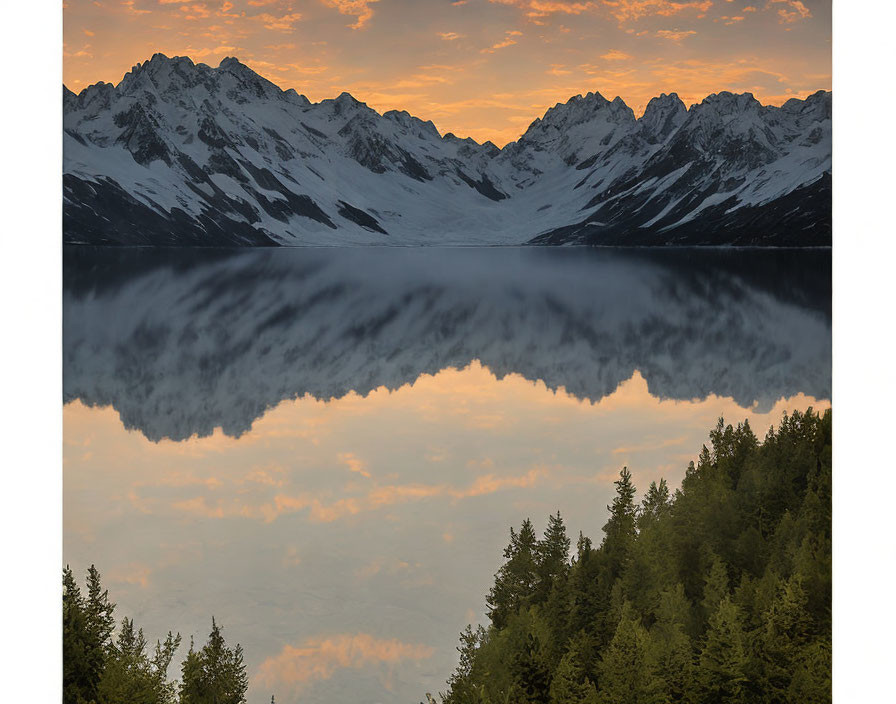 Scenic sunset view of snow-capped mountains, lake reflection, and forest.