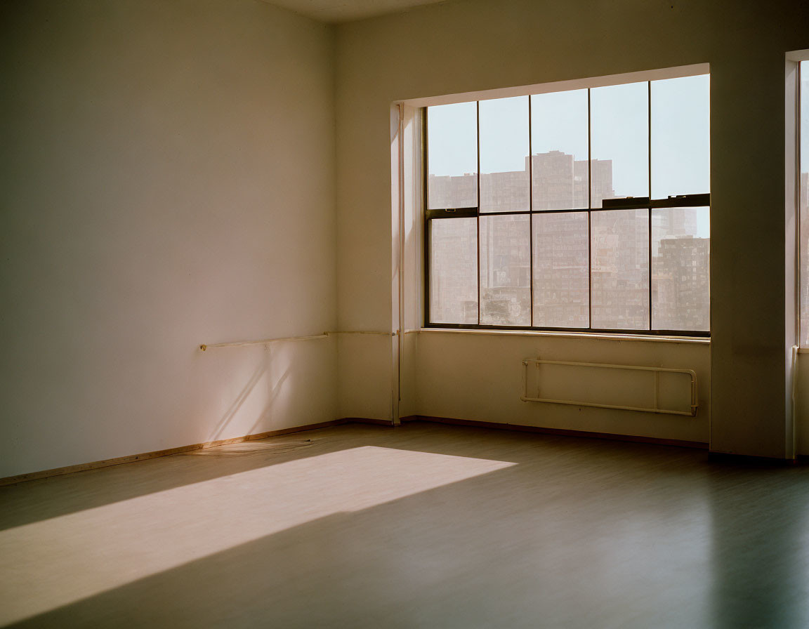 Beige-walled room with city view window, sunlight squares, and radiator