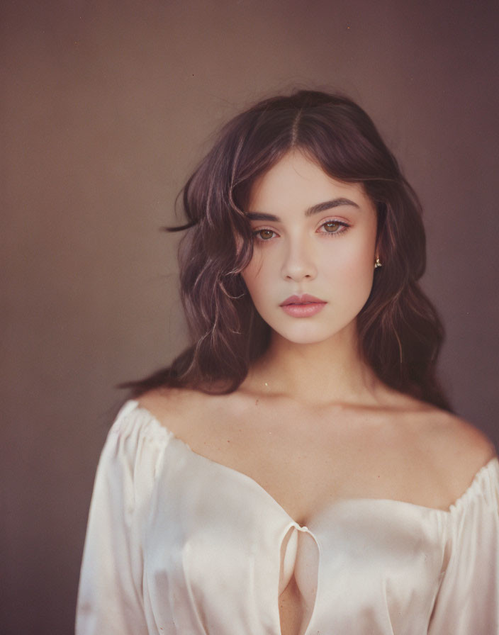 Portrait of woman with dark hair and eyes in white blouse with keyhole neckline.