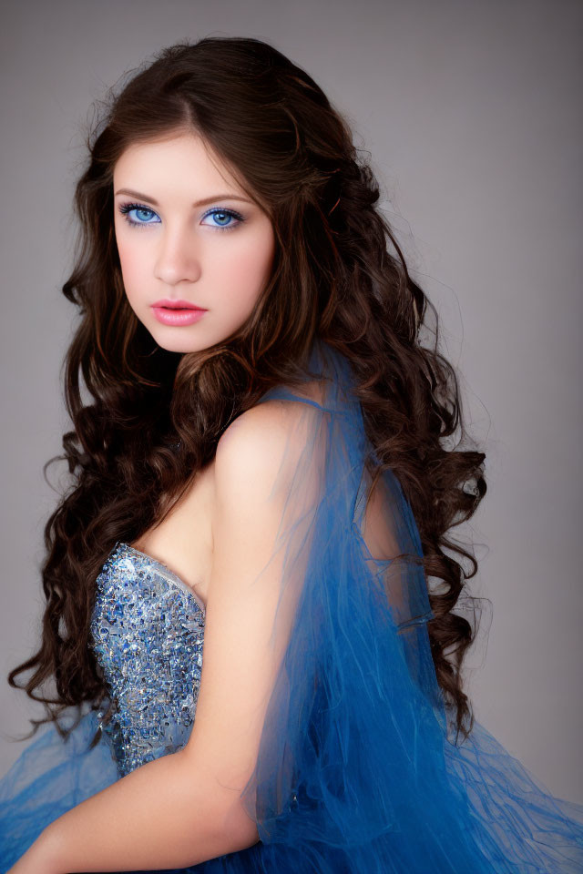 Young woman with long, curly brown hair in blue sequined dress