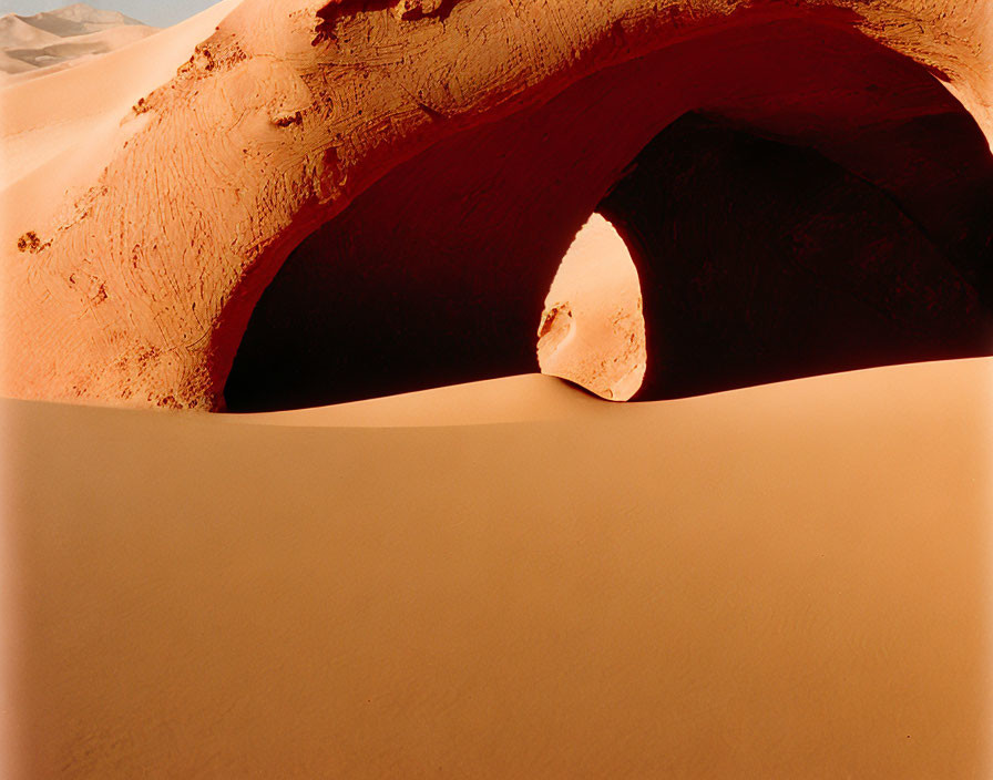 Sandy arch with shadowed interior in desert landscape