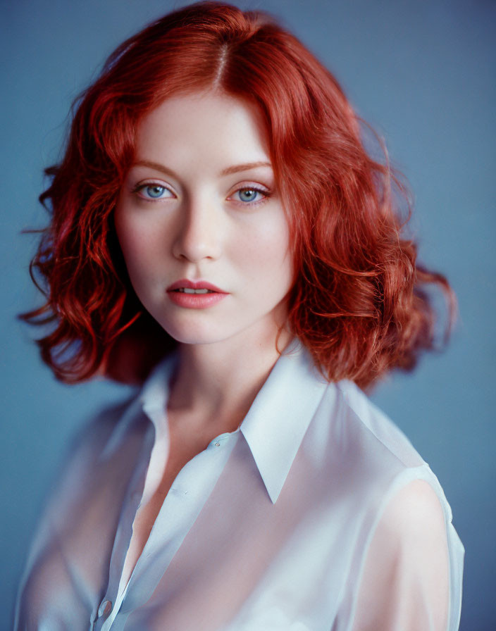 Red-haired woman in white blouse on blue backdrop