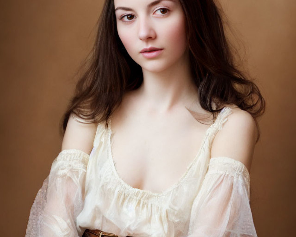 Young woman with long dark hair in white blouse and brown belt against golden backdrop