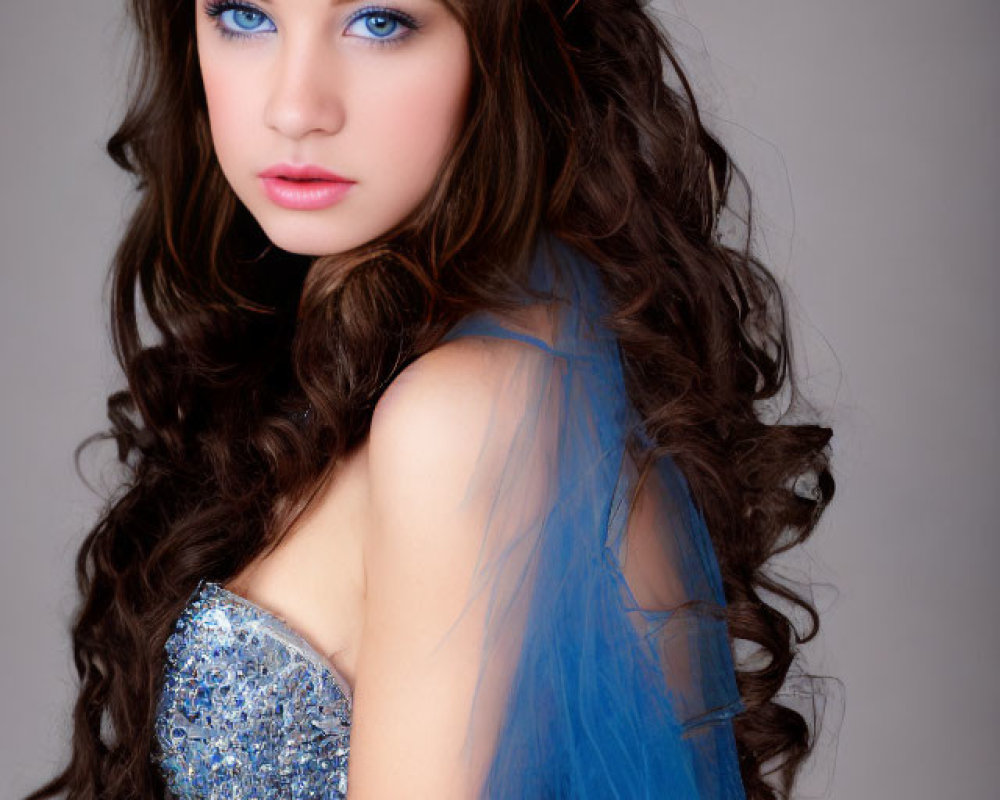 Young woman with long, curly brown hair in blue sequined dress