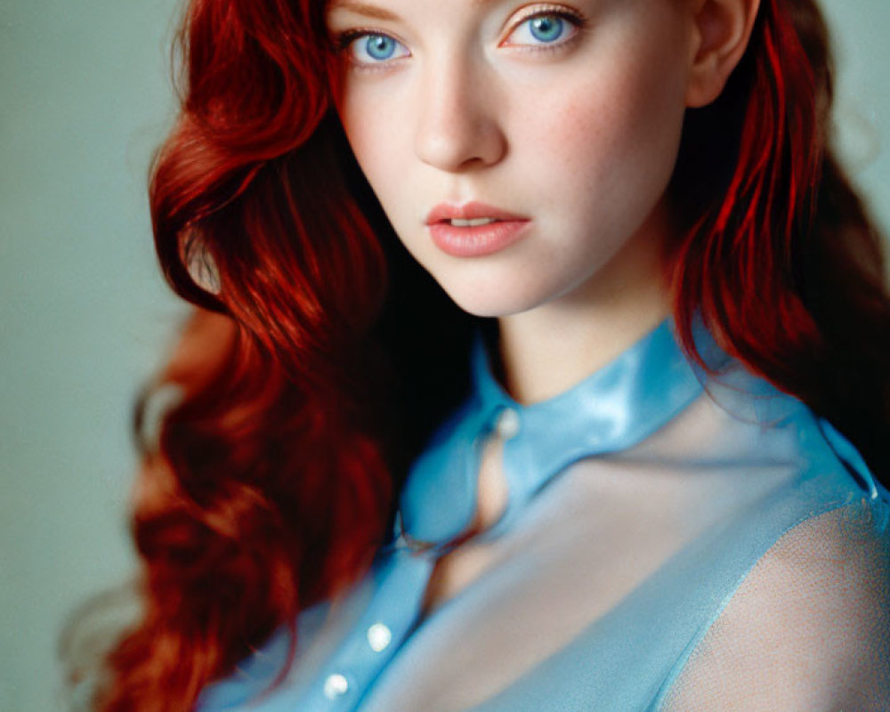 Portrait of a woman with red hair and blue eyes in a sheer blue blouse