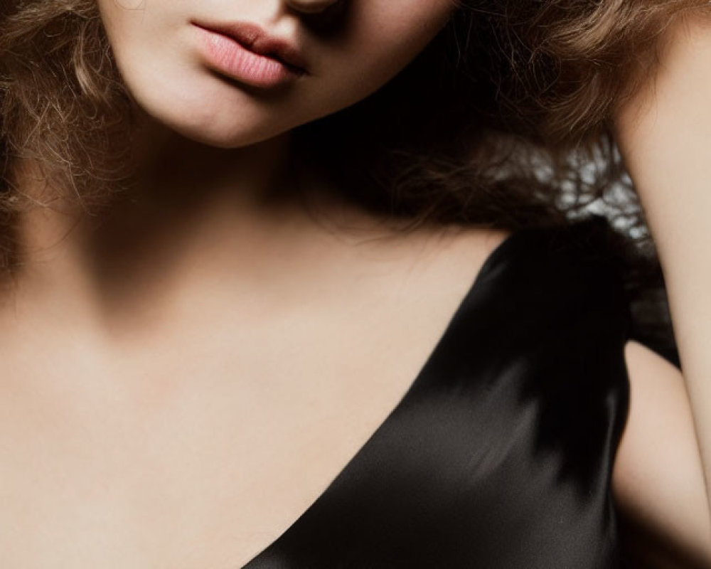 Portrait of person with curly hair in black top on light background