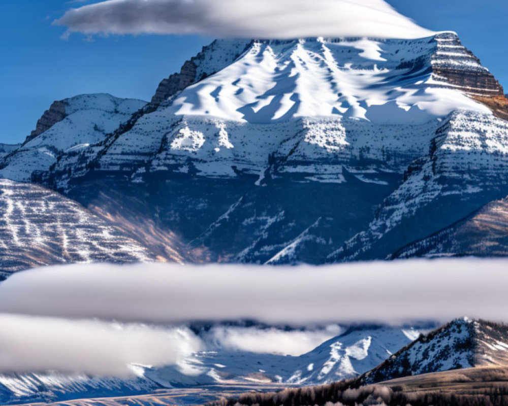 Snow-capped mountain with lenticular clouds and misty layers in blue sky