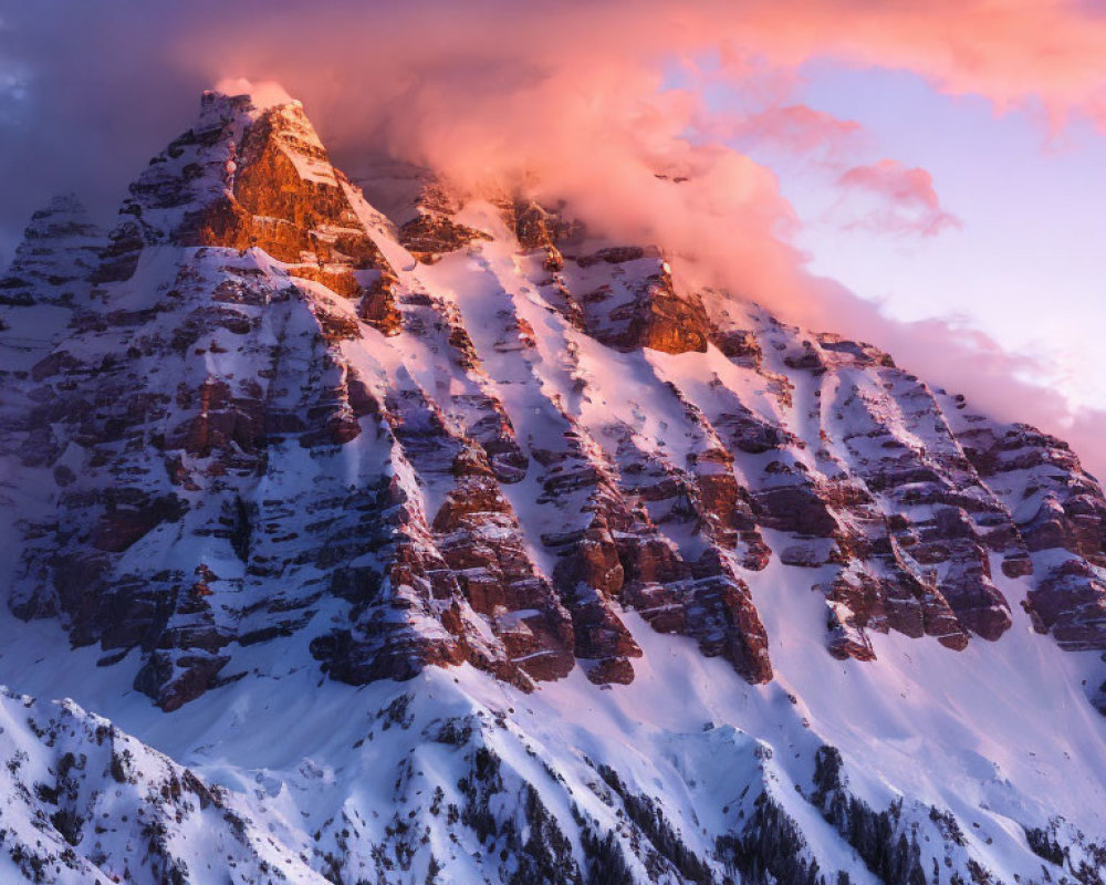 Majestic snow-covered mountain peak at sunset with vibrant orange clouds and alpenglow.