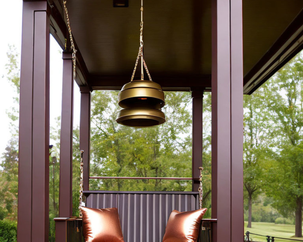 Cozy porch with swing bench, orange pillows, and brass light fixture overlooking grassy area