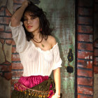 Dark-haired woman in white blouse and patterned skirt leaning against wall with bottle nearby