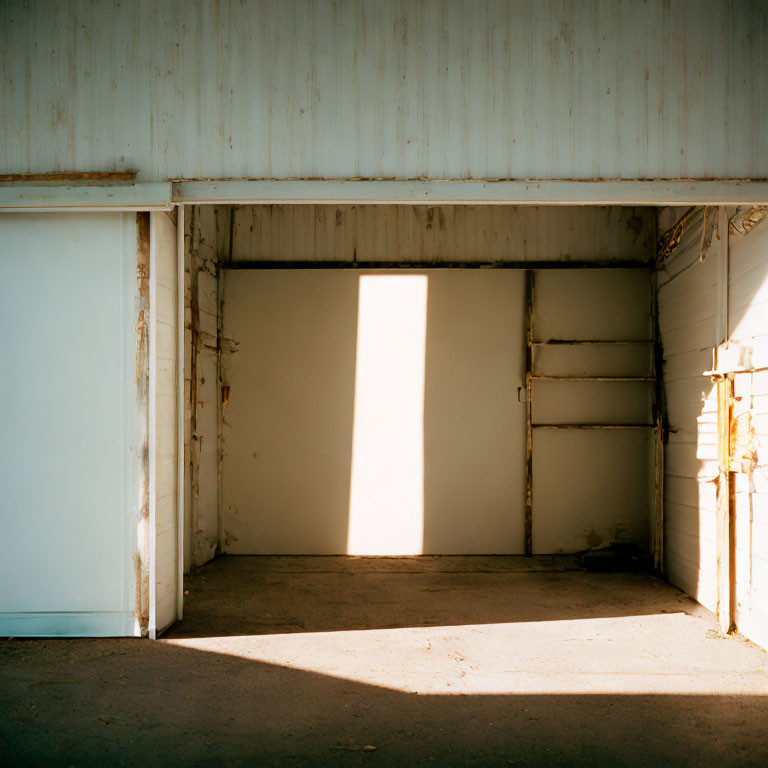 Sunlight illuminates empty garage with white walls