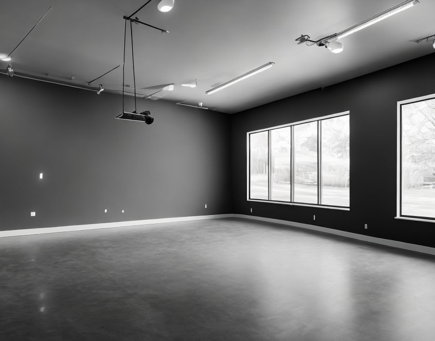 Empty Room with Gray Walls, Polished Concrete Floor, Track Lighting, and Large Windows with Tree View