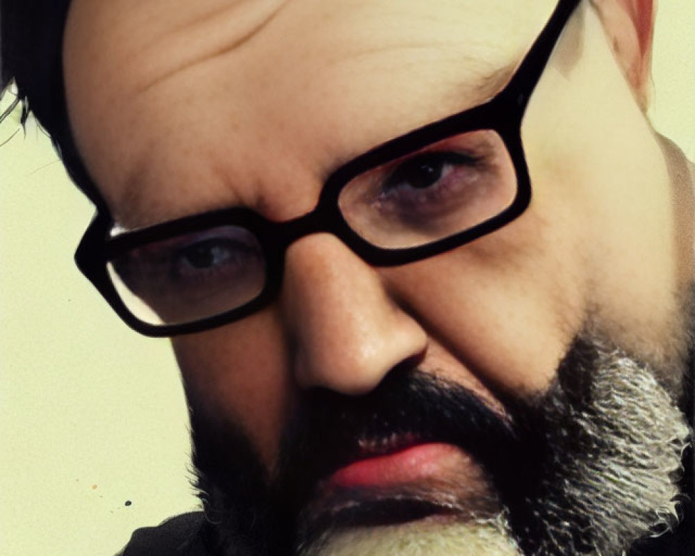 Serious man with thick-rimmed glasses, beard, and mustache portrait.