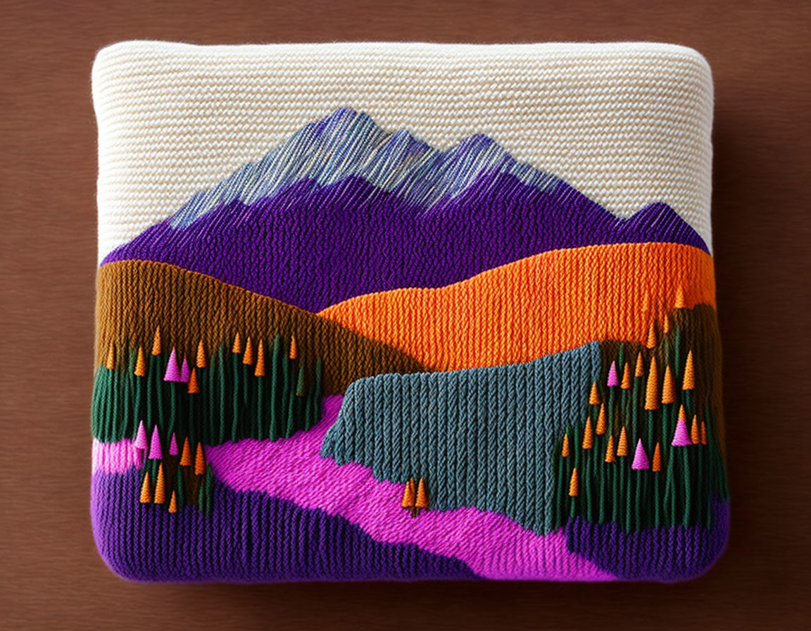 Vibrant embroidered mountain landscape with purple peaks, orange hills, green trees, and blue lake