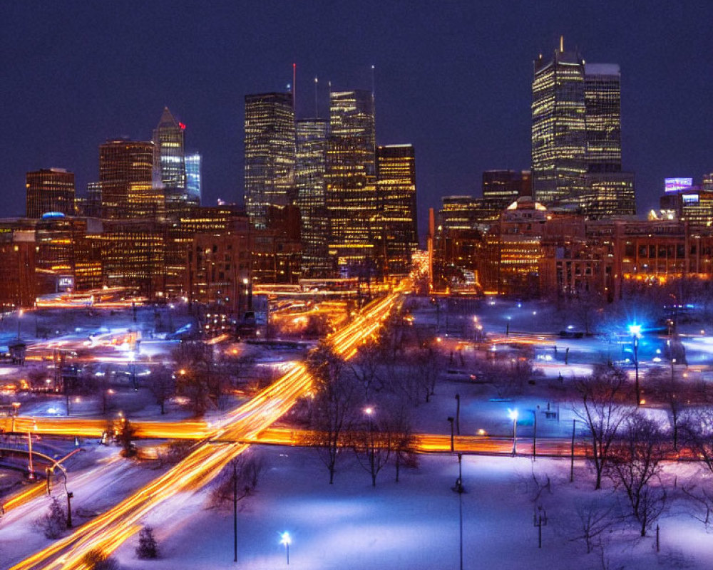 Snow-covered nighttime cityscape with illuminated buildings, streets, and vibrant light trails