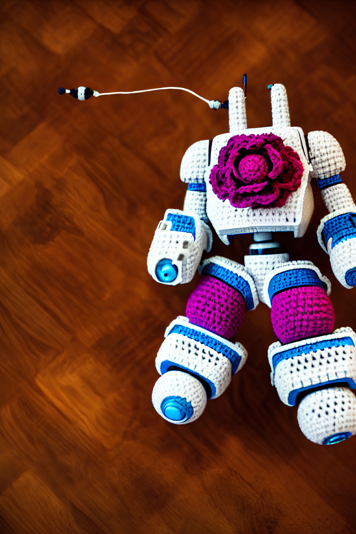 White and Purple Crocheted Robot with Rose on Wooden Floor