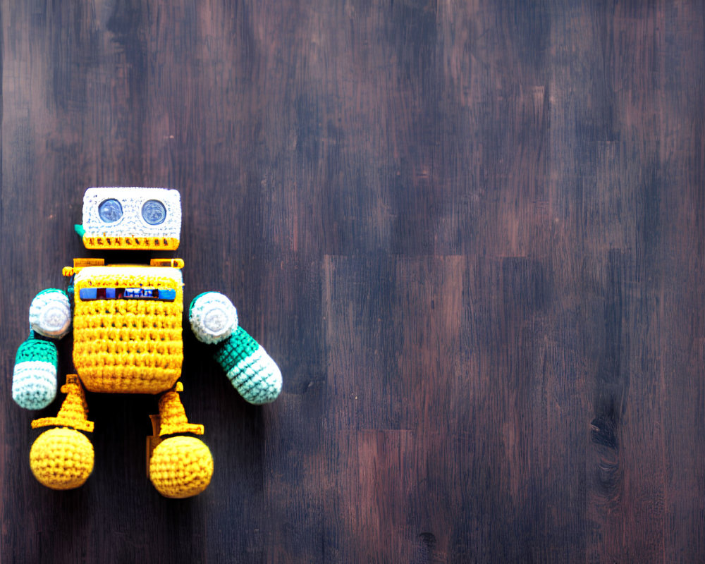 Handmade Crochet Robot Toy in Yellow and Blue on Dark Wooden Background