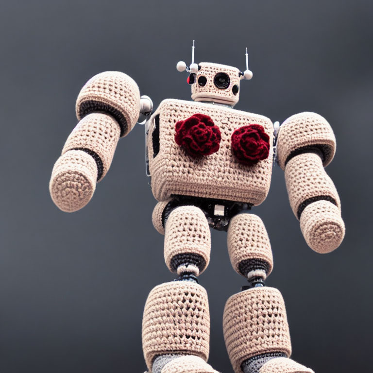 Knitted robot with metallic body and red flowers on chest against grey background