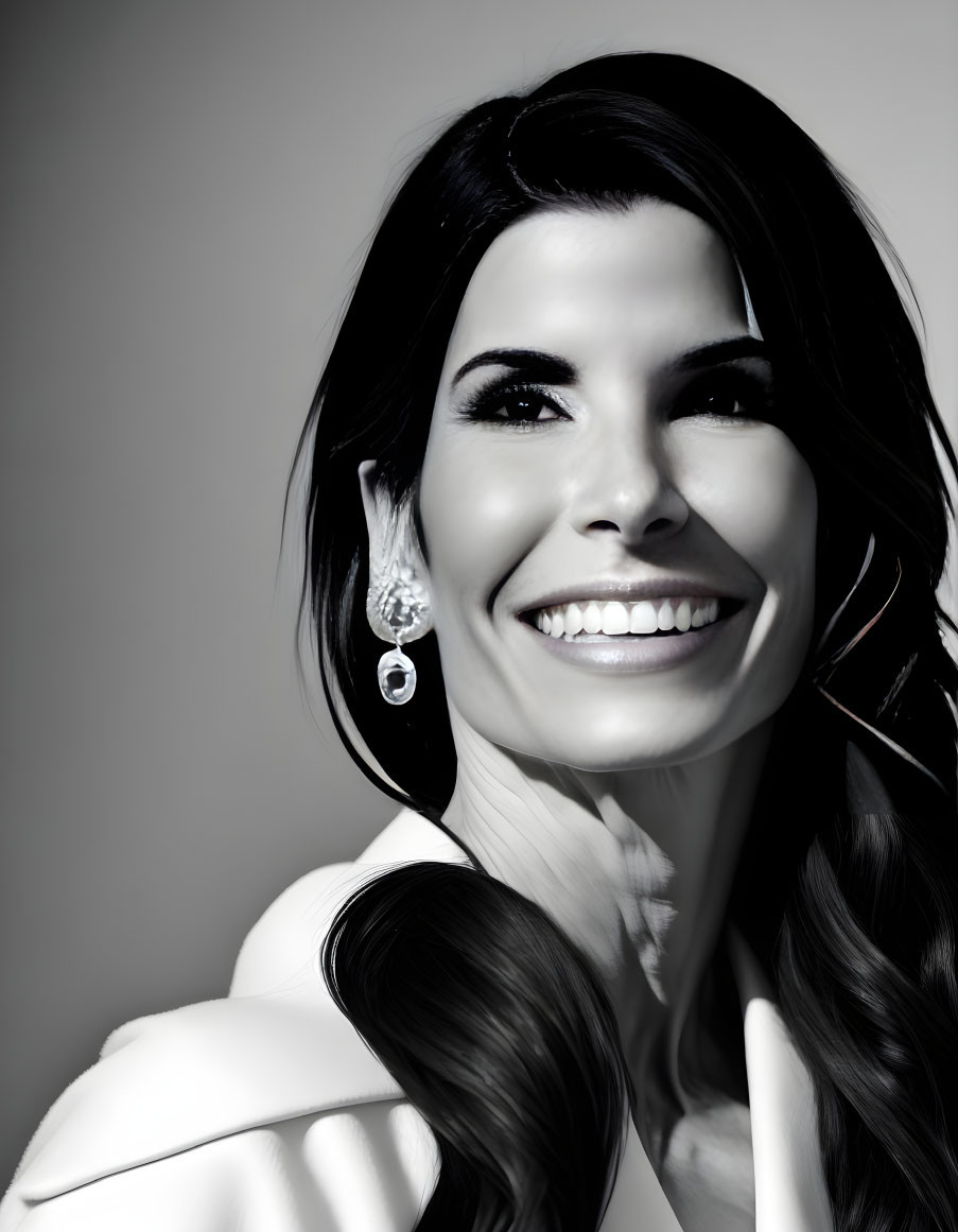 Smiling woman with earrings and shoulder-length hair in black and white portrait