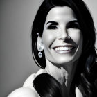 Smiling woman with earrings and shoulder-length hair in black and white portrait