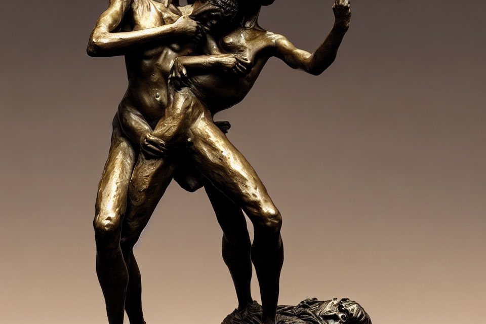 Dynamic bronze statue of intertwined figures in emotional pose on warm background