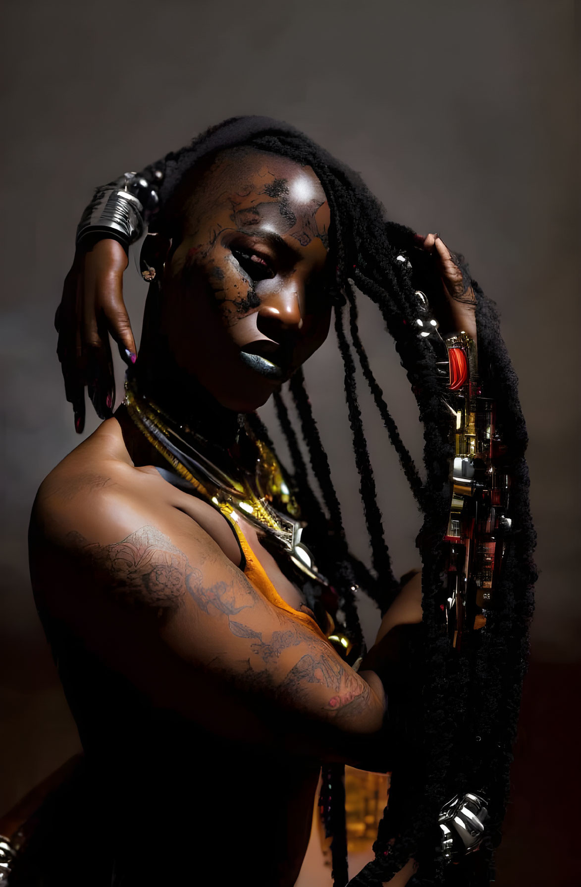 Dramatic pose of woman with dark makeup and braided hair in golden and red jewelry