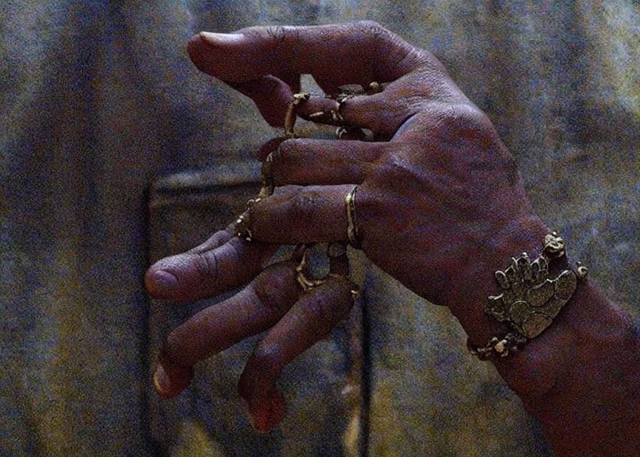 Close-up of hands with multiple gold rings, one resembling a crown