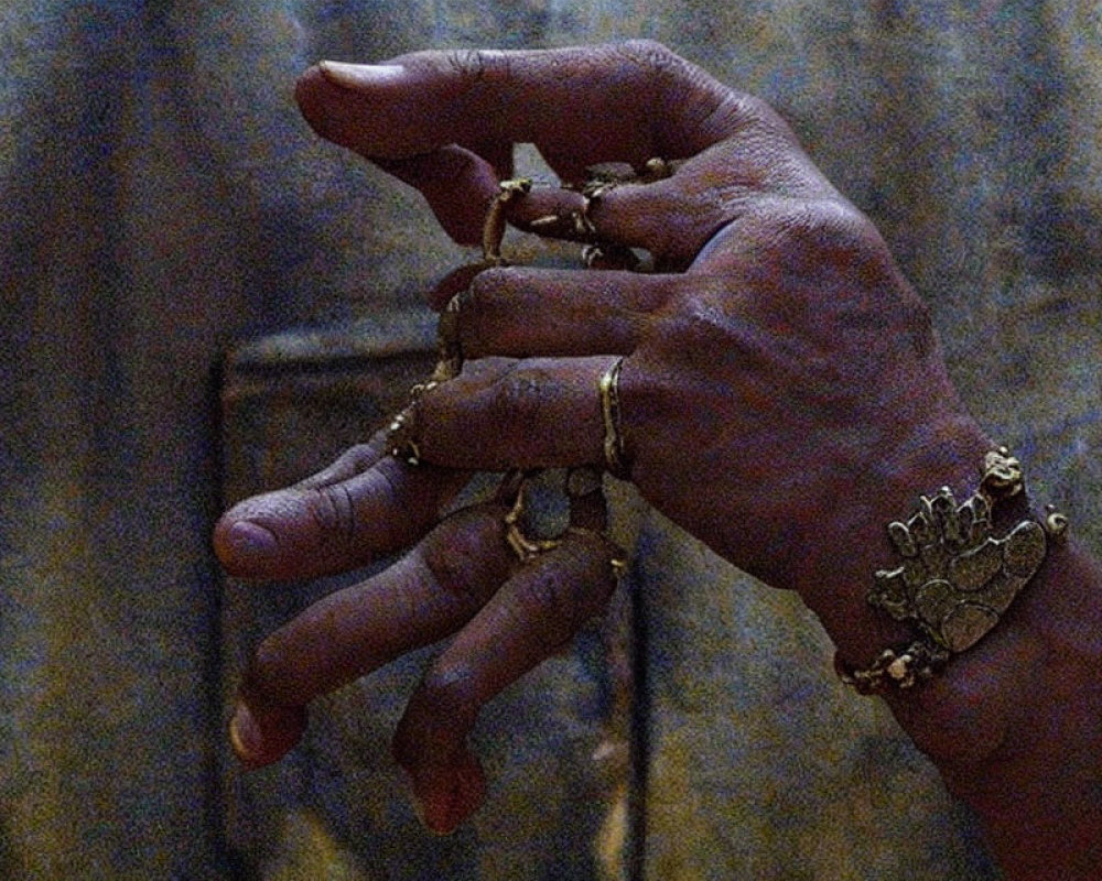 Close-up of hands with multiple gold rings, one resembling a crown