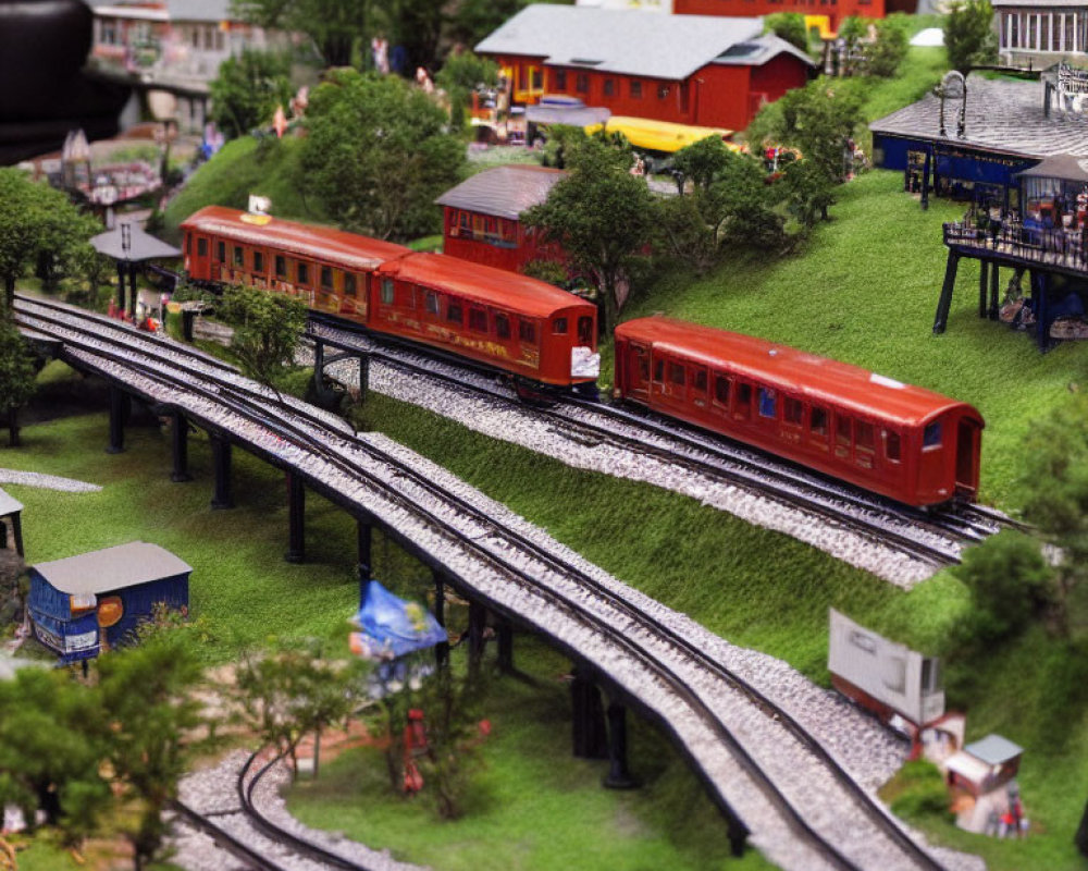 Detailed miniature model train set with red carriages crossing landscape, tiny buildings, trees, and figurines